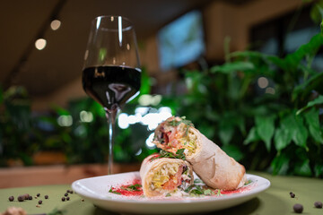 vegetarian pita roll with tomato, salad and cheese on white plate and red wine