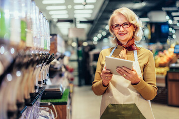 Woman working at a grocery store and using tablet