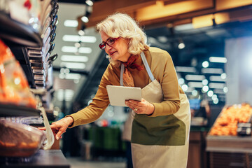 Senior woman checking shelf with groceries in grocery