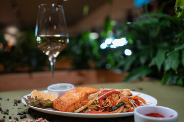 roasted salmon steak with wok vegetable and sauce on white plate in restaurant