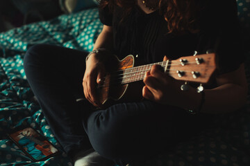 Mujer tocando ukulele en su habitación. Concepto de musica.