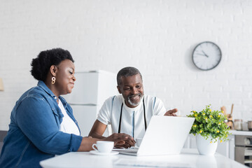 cheerful senior african american couple looking at laptop during video call.