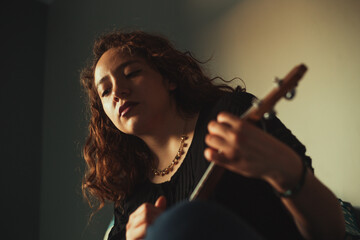 Obraz premium Mujer tocando ukulele en su habitación. Concepto de musica.
