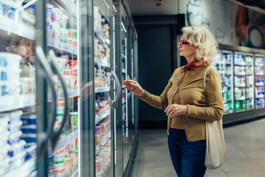 Senior woman at supermarket buying milk products