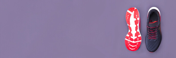 A pair of black sneakers with a red sole, one of which is turned upside down, on a dark background. The concept of a healthy lifestyle. Banner. Copy space