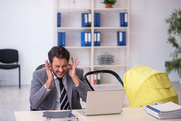 Young male employee looking after new born at workplace