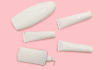 White cosmetic bottles on a pink background. Cream for body care.