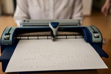 Blind woman using braille typewriter. 