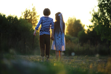 Children walk in the summer in nature. Child on a sunny spring morning in the park. Traveling with...