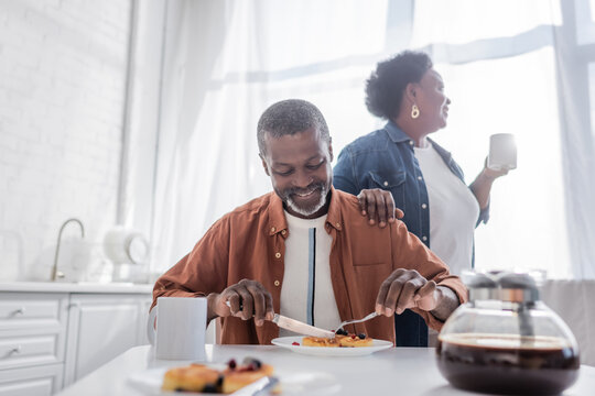 senior african american man having breakfast near happy wife.