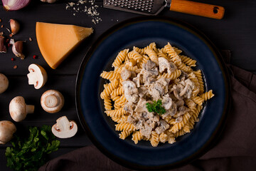 Fusilli pasta, with champignons in cream sauce, top view, with ingredients, on a wooden table, no people,