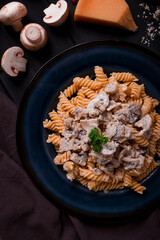 Fusilli pasta, with champignons in cream sauce, top view, with ingredients, on a wooden table, no people,