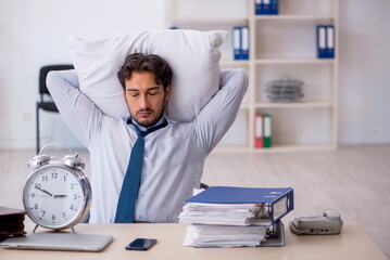 Young male employee in oversleeping concept