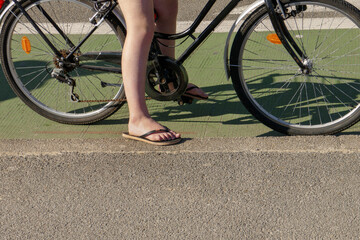 jambes de jeune fille en tongs sur un vélo
