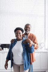 happy and senior african american man hugging cheerful wife.