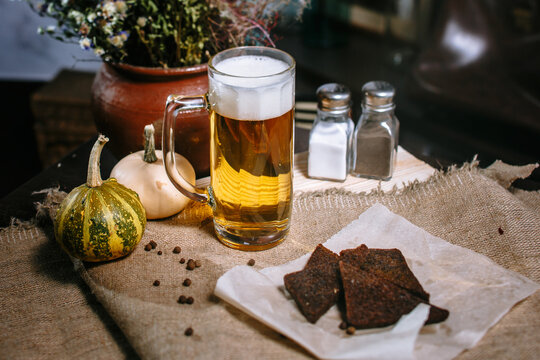 Beer in a large mug, standing on the table. Fried toast from black bread in a plate.