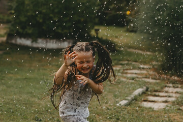 Little girl running in the summer rain.