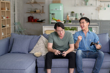 Young smiling gay couple playing video games in the living room at home, LGBTQ and diversity