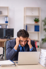 Young male employee and too much work in the office