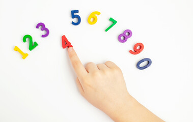 The child uses his index finger to move the number four up. Early education. We learn colors and count from zero to ten