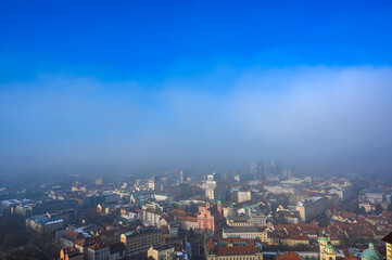 Fototapeta na wymiar Landscape view on the Ljubljana city from the castle during a windy foggy sunny weather in the winter