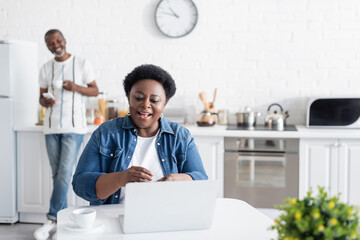 happy african american woman looking at laptop during video call.