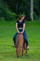girl riding a pony on a green lawn