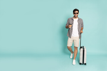 Happy young man traveler drag luggage isolated on green background, Tourist male having cheerful holiday trip concept, Full body composition