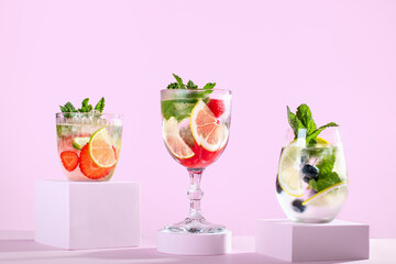 Summer refreshing fruit and berry infused detox water on podiums in pink color, creative summer beverages background