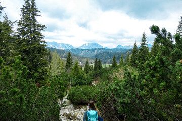 Woman with backpack on a hiking trail with view on cloud covered mountain peaks of the Hochschwab Region in Upper Styria, Austria. Plateau full of bushes in beautiful Alps, Europe. Freedom vibe. Rain