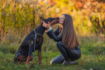 girl sitting near a doberman dog breed in nature