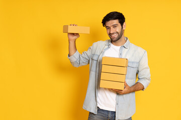 Man holding package parcel box isolated on yellow background, Delivery courier and shipping service...