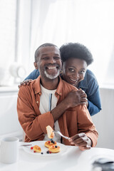 joyful and senior african american couple looking at camera during breakfast.