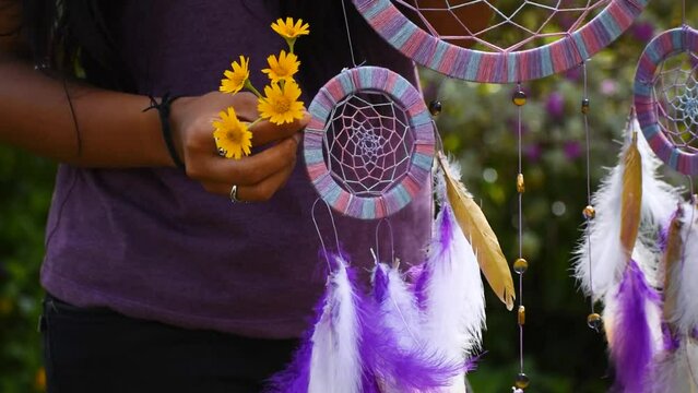 Indian Woman with flowers in hand holding dreamcatcher in garden. Ritual decoration for good dreaming. Atmospheric mood and spirituality concept