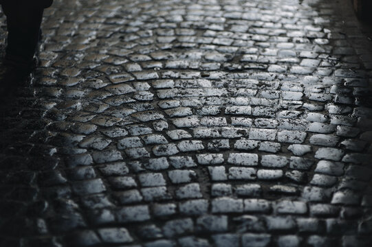 Dark gray paving stones close-up with traces of slush and wet snow. Texture of old stone. Road surface. vintage, grunge.