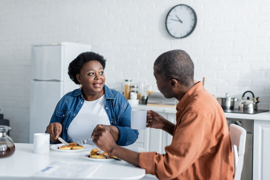 senior african american woman talking with husband during breakfast at home.