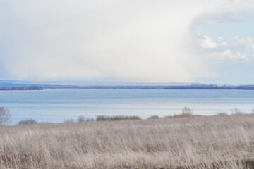 Scenic spring landscape with dry grass on field.