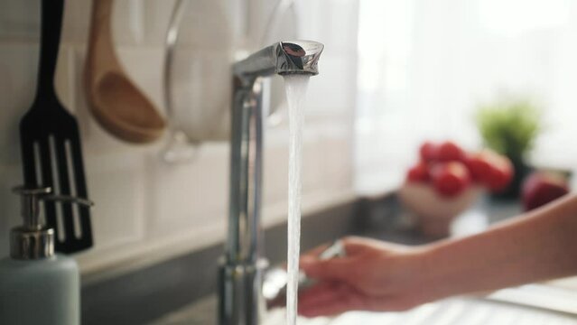 Woman pouring a tap water in glass, concept of pure drinking water.