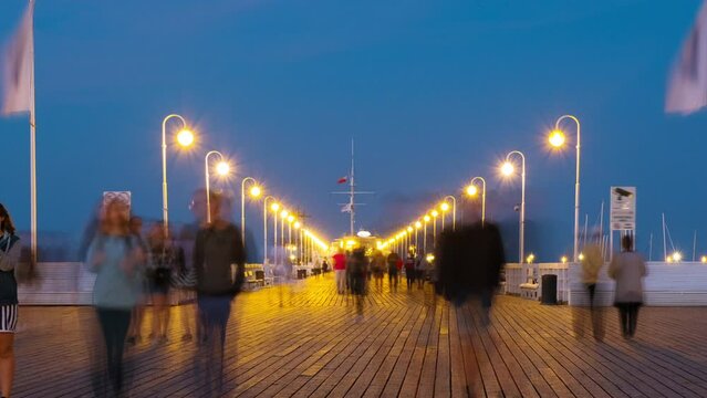 Sopot, Poland. An evening time-lapse of a long wooden pier in Sopot, Poland, with a view of blurred people and a blue sky, panning video