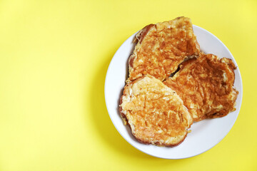 Delicious egg sandwiches in a plate on a yellow background. A hot homemade sandwich with a place to copy.