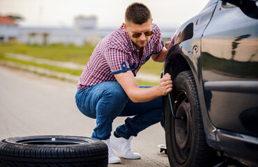 Man changing wheel on his car. Transportation, traveling concept