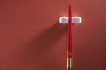 chopsticks on chopstick rest against red background