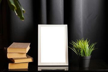 Stylish and modern workspace with white empty frame, books and houseplant on home or studio.