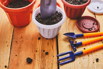 Flower pots and set decorative gardening tools shovel, rake and pitchfork on a wooden background.