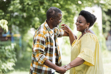 happy senior african american couple dancing in park.