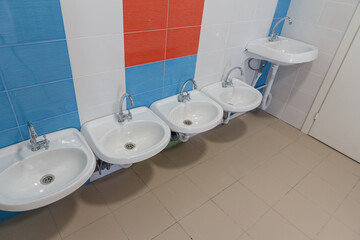 Toilet in the kindergarten. Small sinks for washing hands in the toilet of the kindergarten.