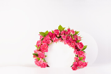 Spring fresh pink roses as decorative framing of circle arch with two podiums for presentation cosmetic products, goods, mockup on white background, copy space. Template for advertising, design.