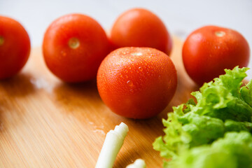Fresh vegetables for salad lie on a wooden table with a cutting board. Close-up.