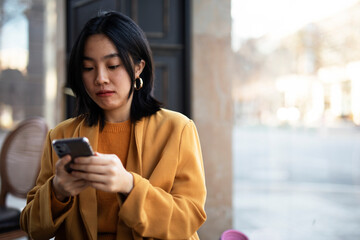Fototapeta premium Happy Chinese girl checking phone. Beautiful young girl typing a message..