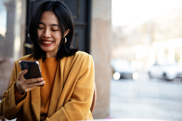 Happy Chinese girl checking phone. Beautiful young girl typing a message..